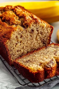 a loaf of banana bread sitting on top of a cooling rack next to some bananas