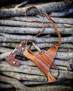 two leather holsters sitting on top of logs