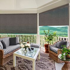 a living room with wicker furniture and large windows covered in roman shades on the outside