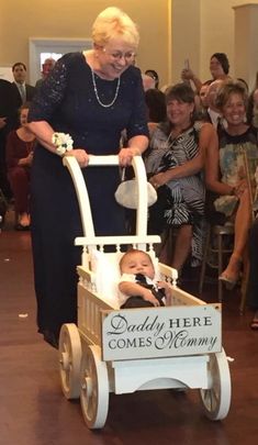 an older woman pushing a baby in a wagon with the words dolly here comes mommy on it