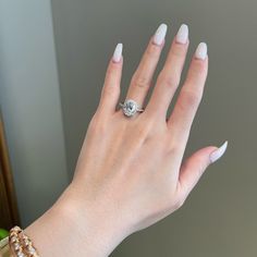 a woman's hand with white nails and a ring