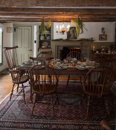 a dining room table with chairs and plates on it in front of a fire place