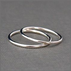 two silver rings sitting on top of each other in front of a black background,