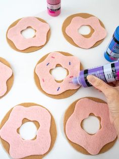 someone is painting doughnuts with pink icing