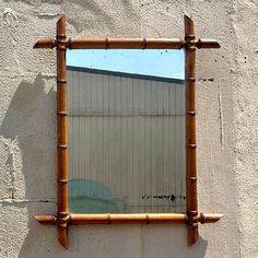 a mirror hanging on the side of a wall with bamboo sticks sticking out of it