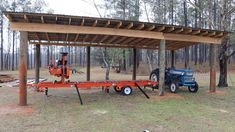 a tractor pulling a trailer under a wooden structure