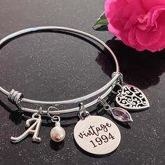 Celebrate her milestone birthday with this thoughtful 'vintage 1994' personalized 30th birthday bracelet. The stainless steel adjustable bangle bracelet has a 'vintage 1994', cream pearl, filigree heart, birthstone, and a script initial for personalization.  The bracelet comes beautifully packaged and ready to gift. Gift for Wife, Spouse, Girlfriend, Sister, Goddaughter, Granddaughter, Daughter, Niece, Family member, Cousin, Coworker, or Friend.  Gift from coworker, daughter, sister, mother, fri Vintage Adjustable Jewelry For Mother's Day, Personalized Vintage Jewelry For Birthday, Vintage Personalized Jewelry For Birthday, Classic Adjustable Charm Bracelet For Anniversary, Adjustable Bangle Charm Bracelet For Anniversary, Classic Personalized Charm Bracelet For Anniversary, Anniversary Name Bracelet With Birthstone, Adjustable Stainless Steel Charm Bracelet For Anniversary, Personalized Vintage Charm Bracelet Gift