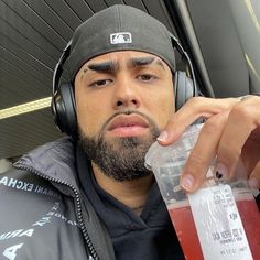 a man wearing headphones and holding a drink