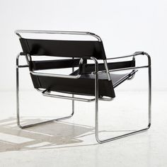 a black leather chair sitting on top of a white floor next to a metal frame