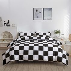 a black and white checkered comforter set on a bed with two pictures above it