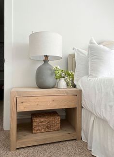 a nightstand with a lamp on it next to a bed