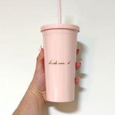 a person holding a pink cup with a straw in it