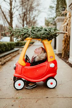 a child in a toy car with a christmas tree on top