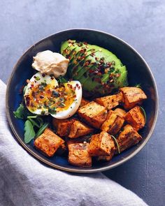 a blue bowl filled with tofu, avocado and an egg on top