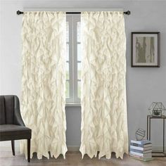 a white curtain with ruffles hanging on the side of it in front of a window