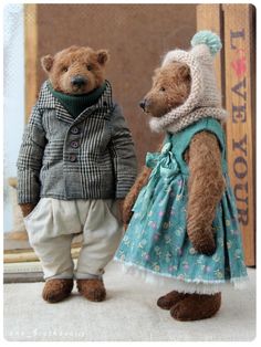 two teddy bears dressed in clothes standing next to each other