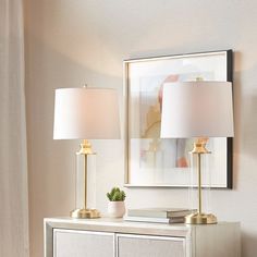 two lamps sitting on top of a white dresser