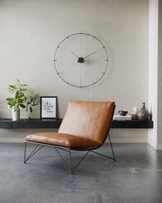 a chair sitting in front of a clock on the wall