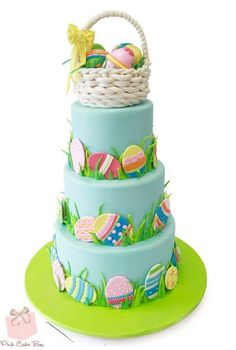 a three tiered cake decorated with easter eggs and grass, on top of a green plate