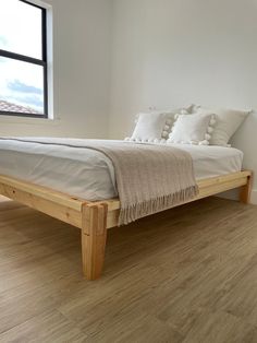 a bed sitting on top of a hard wood floor next to a window in a bedroom