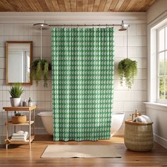 a bathroom with a green shower curtain next to a white bath tub and wooden floors