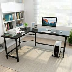 a desk with a computer on it in front of a book shelf and bookshelf