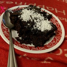 a piece of chocolate cake on a red and white plate with two silver spoons