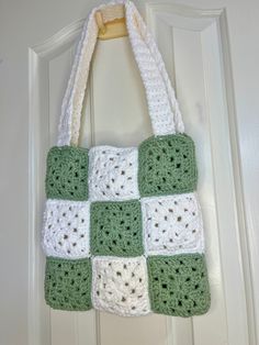 a green and white crocheted bag hanging on a door