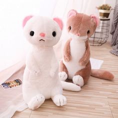 two stuffed animals sitting next to each other on a wooden floor