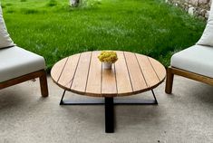 two chairs and a table with flowers on it in front of a grassy yard area