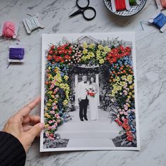 a person is holding up a photo with flowers on it and scissors next to them