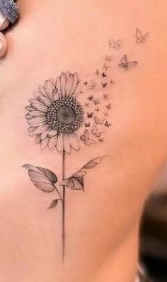 a woman's back with a tattoo on it and a sunflower in the middle