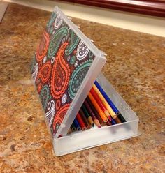 an open container filled with colored pencils on top of a counter