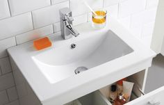 a bathroom sink sitting under a mirror next to a counter top with soap and toothbrushes