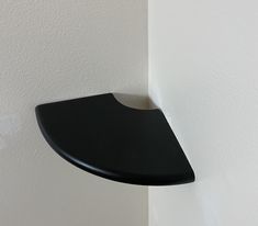 a black shelf mounted to the side of a white wall