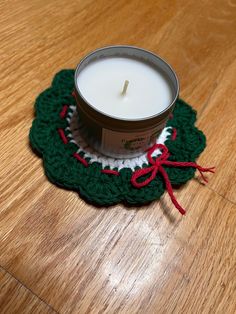 a candle sitting on top of a wooden table next to a crocheted doily