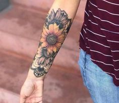 a person with a sunflower tattoo on their arm holding the hand of another person