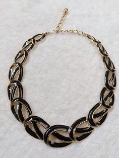 This is a simple but elegant vintage black and gold enamel  large chain/loop necklace from 1960'. It is in excellent condition without any fading or damage. This is a quality and very versatile piece and would match well with many different styles. It has a hook closure and adjustable length.  Measurements:  width 14 Inches length: 14-17 Inches, adjustable  Materials: Black Enamel, Gold Plated Alloy Designer/Mark: Trifari Loop Necklace, Chain Loop, Vintage Trifari, Crown Trifari, Jewelry Model, Chain Gold, Necklace Black, Gold Enamel, Collar Necklace