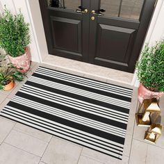 a black and white striped door mat sitting on top of a floor next to potted plants