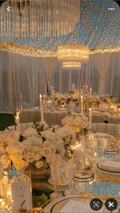 the table is set with white flowers, candles and place settings for an elegant dinner