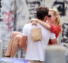 a man and woman hugging each other while holding shopping bags in their hands on the street