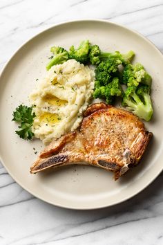 a white plate topped with meat, mashed potatoes and broccoli