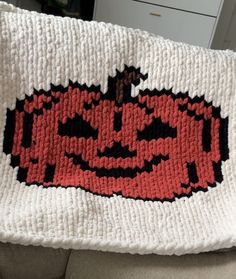 a crocheted pumpkin pillow sitting on top of a couch