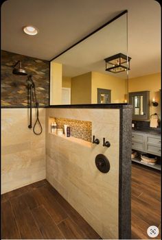 a bathroom with a shower, sink and mirror on the wall next to wood flooring