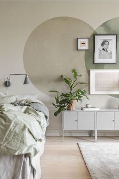 a bed room with a neatly made bed and a plant on the dresser next to it