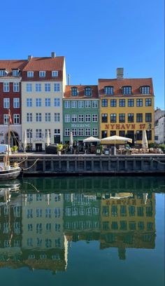 boats are docked in the water next to some colorful buildings and umbrellas on a sunny day