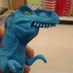 a person holding a toy dinosaur in their hand