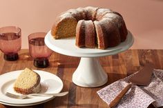 a bundt cake sitting on top of a wooden table next to plates and glasses