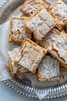 several pieces of cake sitting on top of a silver plate covered in powdered sugar