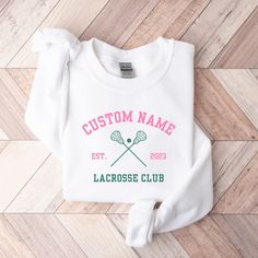 *SIZE GUIDE + MEASUREMENTS + COLORS are included in the listing photos. *ADDITIONAL BABY SIZES are available upon request. Elevate your everyday look with our Custom Lacrosse Club Shirt.  Made from a breathable, luxuriously soft fabric with just the right amount of stretch. Featuring a crewneck style and a relaxed fit for a comfort that goes everywhere with you. The perfect essential or gift. T-SHIRT DETAILS: -Premium printed detail across chest -Premium airlume combed and ring-spun cotton -If you would like to adjust the design color, or would like a shirt color that isn't listed, we can make that happen for you! SWEATSHIRT DETAILS: -Premium cotton blend -Premium printed detail across chest -Finished with ribbed collar, cuff & hem -Brushed inner fleece for added softness -If you would lik Custom Logo Crew Neck Tops For Sports Season, Custom Logo Crew Neck Tops For College, Customizable White Sweatshirt For Sports, Crew Neck Tops With Custom Logo For Sports Season, White Customizable Sweatshirt For Sports, Crew Neck Top With Custom Logo For College, White Crew Neck Top With Custom Logo, Customizable Sporty Long Sleeve Tops, Customizable Long Sleeve Sporty Tops